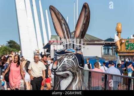 Painted head of one of the Hares about Town sculpture art trail hares on a hot summer day, with a busy seafront at Southend on Sea, Essex. People Stock Photo