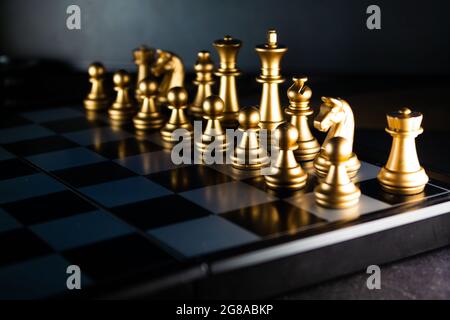 A horizontal shot of cool gold chess pieces in the starting position Stock Photo