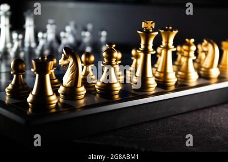 A horizontal shot of cool gold chess pieces in the starting position reflected on the board Stock Photo