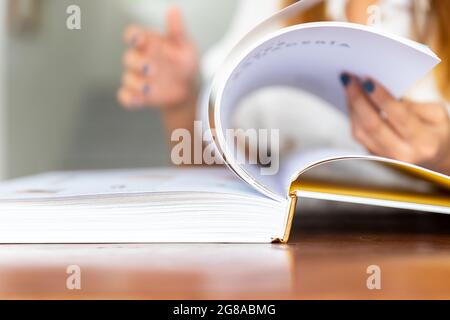 selective focus of woman's hands turning the pages of a book Stock Photo