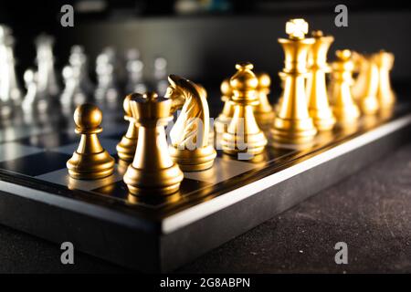 A horizontal shot of cool gold chess pieces in the starting position reflected on the board Stock Photo