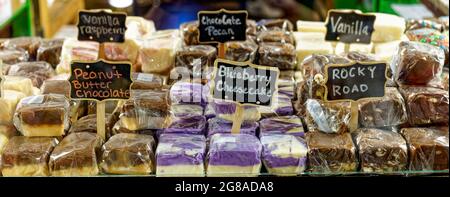 banner of many flavors of fudge wrapped in plastic with signs behind glass Stock Photo