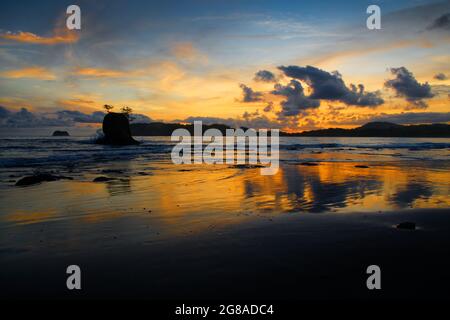 Evening scenery on the beach in Nicoya peninsula, Costa Rica. Pacific ocean coast bay with dramatic clouds on the sky, holidays in paradise. Trees, is Stock Photo