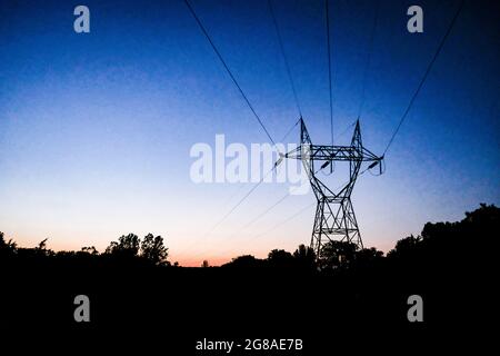 Electric transmission towers and wires at sunset. Stock Photo