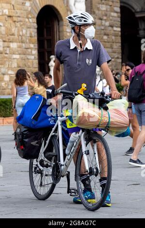 Man tourist with a bike next to Uffizi museum and David sculpture, wearing face masks during covid 19 quarantine in Italy. Slow reopening Stock Photo