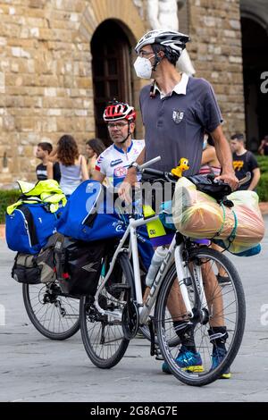 Man tourist with a bike next to Uffizi museum and David sculpture, wearing face masks during covid 19 quarantine in Italy. Slow reopening Stock Photo