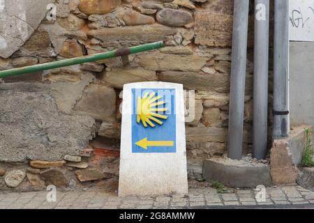 Camino de Santiago (Way of Saint James). Traditional yellow direction sign of the Camino de Santiago in Ponferrada in Castile and León, Spain. Ponferrada is the last major town on the French route of the Camino de Santiago before it reaches Santiago de Compostela. The scallop shell, also known as the Shell of Saint James is depicted in the sign as a traditional symbol of the pilgrimage to Santiago de Compostela. Stock Photo