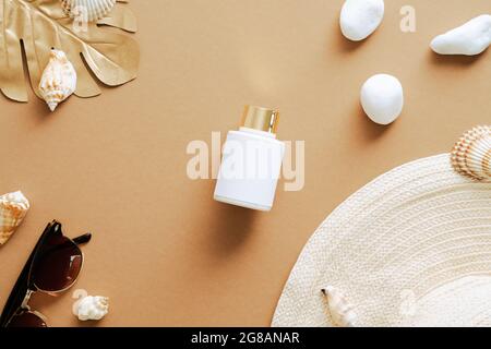 Flat lay composition with sunscreen lotion, straw hat, seashells, sunglasses on sand colored background. Summer vacation concept top view. Stock Photo