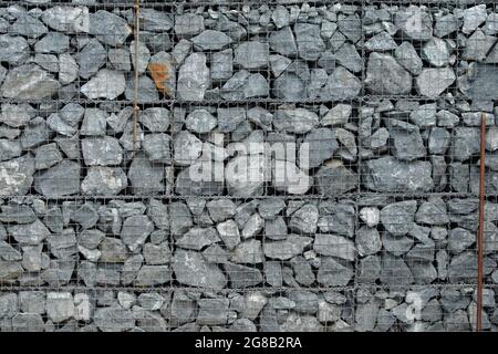 The texture of a fence made of many gray stones, reinforced with a metal mesh. Background. Stock Photo