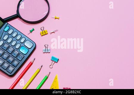Various office supplies on a pink background. Back to school concept. View from above. Calculator and pencils Stock Photo