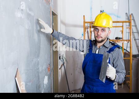 Adult male is checking the quality of the work done after the plaster wall Stock Photo