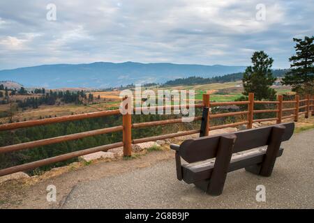 Top view of a hilly landscape behind a log hedge with mountains and forest, cloudy sky in the background Stock Photo