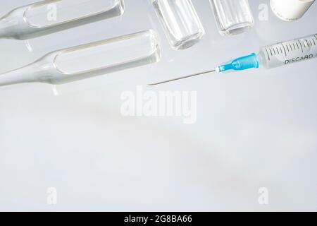 medical vaccine vials or bottles and a syringe on table over blue background. blank vial template for label. empty white label on the bottle for text Stock Photo