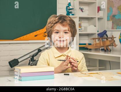 Kids Science education concept. School kids against green chalkboard. Little student boy happy with an excellent mark. Stock Photo