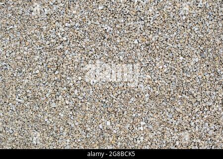 Dry white limestone ballast flat full frame background. Small gray dusty broken macadam stones texture. Stock Photo