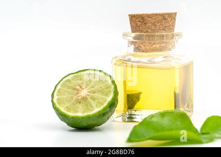Beautiful packshot of Bergamot essential oil in a small glass bottle with cork, fresh bergamot fruit, and green leaf on white background. Blank space Stock Photo