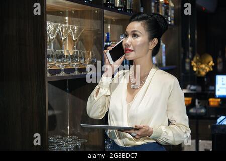 Restaurant owner with digital tablet in hands talking on phone and orgering alcohol and food delivery Stock Photo