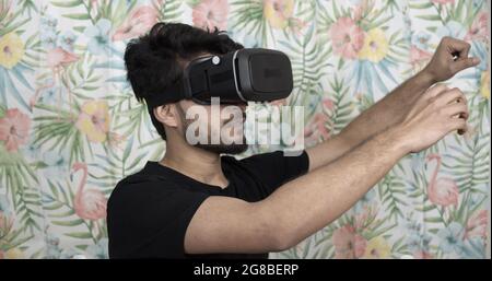 Indian man wearing a VR headset and a flower pattern wall background Stock Photo