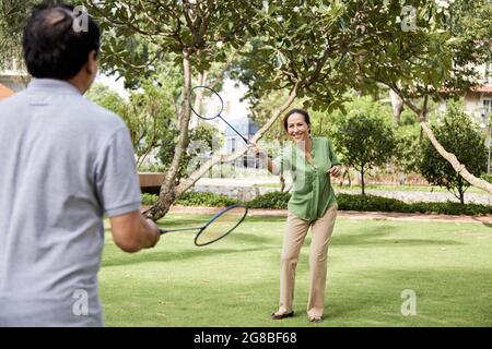 Cheerful senior couple playing bandminton in city park on sunny summer day Stock Photo