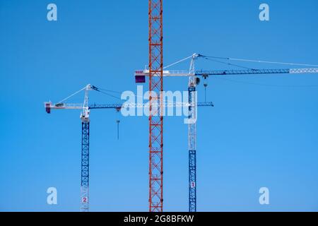 Three tall cranes constriction with blue background Stock Photo