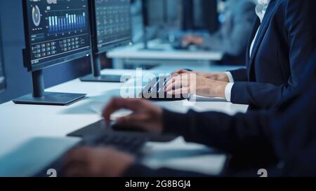 Close Up Hands Shot of a Technical Support Specialist of Software Engineer Working on a Computer in a Dark Monitoring and Control Room. He types on Stock Photo