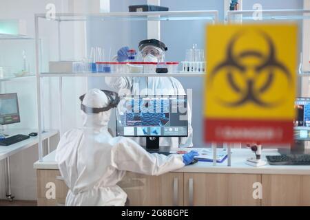Medical staff working in laboratory danger zone dressed in ppe suit. Group of doctors examining vaccine evolution using high tech for diagnosis against covid19. Stock Photo
