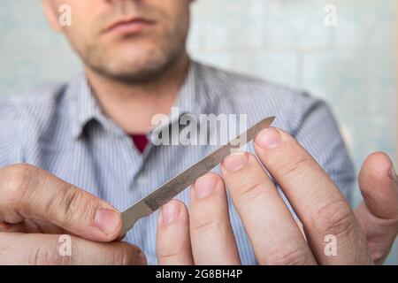 A man uses a nail file to trim his nails on his hand. Close-up. Selective focus. Stock Photo