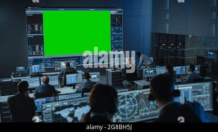 Big Green Screen Horizontal Mock Up in a Mission Control Center Room with Flight Director and Other Controllers Working on Computers. Team of Stock Photo