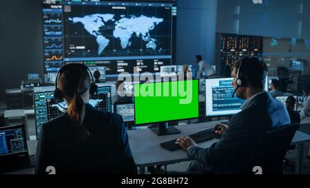 Green Screen Horizontal Mock Up on Computer Display Used by Controller in Surveillance Control Center with Global Map Tracking on a Big Digital Screen Stock Photo