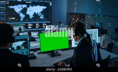 Green Screen Horizontal Mock Up on a Computer Display Used by a Female Technical Client Support Specialist. Team of Engineers Work in Control and Stock Photo
