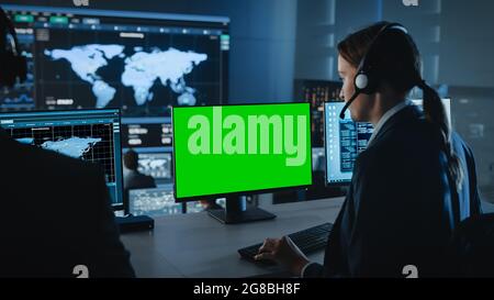 Green Screen Horizontal Mock Up on a Computer Display Used by a Female Technical Client Support Specialist. Team of Engineers Work in Control and Stock Photo