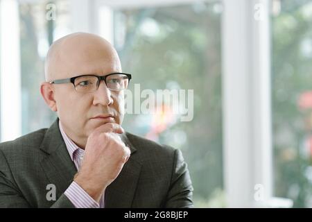 Close-up of pensive mature businessman in eyeglasses standing at office Stock Photo