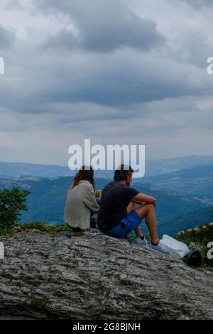 Reggio Emilia, Italy: couple sitting in the mountains, eating and watching the aerial view Stock Photo