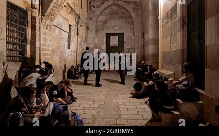 Religious Jews gathered as they mourn at the Iron Gate ( Arabic: Bab al-Hadid ) which leads to the Temple Mount in the Muslim Quarter, on the Jewish feast of Tisha B'Av on July 18, 2021 in Jerusalem, Israel. Jews around the world gathered on the night of July 17 to read from the Book of Lamentations, marking the beginning of Tisha B'Av, the annual fasting day commemorating the destruction of the First and Second Temples in Jerusalem. Stock Photo
