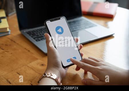 CHIANG MAI, THAILAND, JAN 23, 2021 : Woman hand holding iPhone 12 with social networking service Telegram on the screen. iPhone 12 was created and Stock Photo