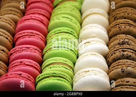 Macaroons in a row close up, colorful sweet background. Strawberry, vanilla and chocolate almond cookies with filling in a store Stock Photo