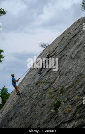 Reggio-Emilia, Italy: People in special equipment and helmet climbing a rock. Alpinist extreme sport Stock Photo
