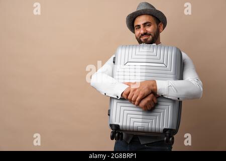 Happy arab man with luggage suitcase against beige background Stock Photo