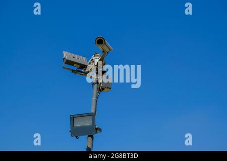 cctv security camera close-up with a lamp on sun battery across blue sky . Security system Stock Photo