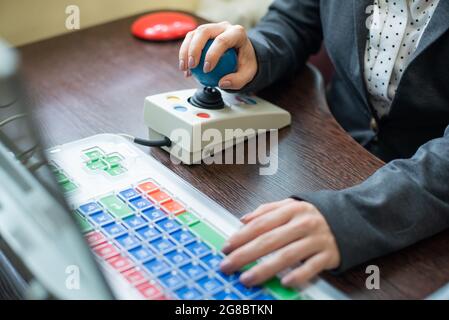 Woman with cerebral palsy works on a specialized computer. Stock Photo