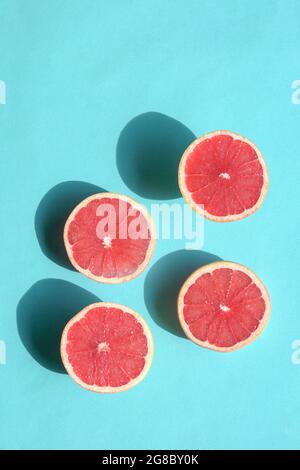 Ripe grapefruit halves on blue background. Top view on harsh sunlight with shadows. Stock Photo