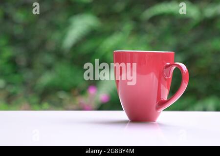 Hot coffee in red cup on table with nature bokeh background. Copy space. Stock Photo
