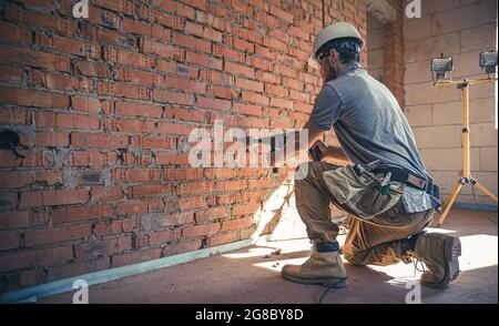Handyman at a construction site in the process of drilling a wall with a perforator. Stock Photo