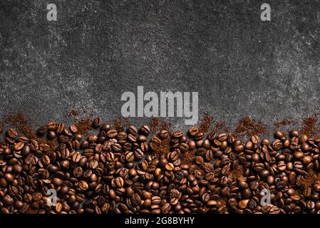 Coffee beans and ground coffee on black background, top view, copy space. Roasted  coffee concept border. Stock Photo