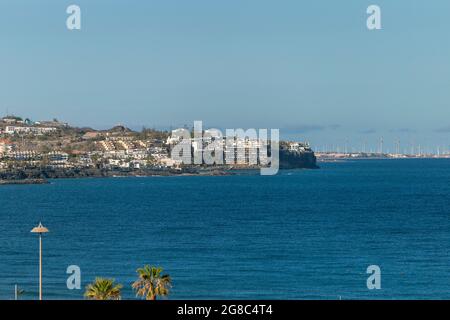 Ocean shore in Maspalomas, Gran Canaria with wind turbines in the background. Stock Photo