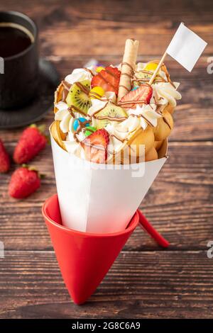 Hong kong or bubble waffle with ice cream, fruits, chocolate sauce and colorful candy Stock Photo