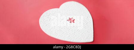 White heart made from puzzle lying on red background Stock Photo