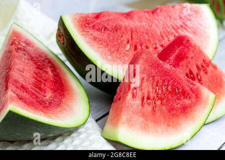 Bright sweet red and green watermelon slices in summer on light table background. Stock Photo