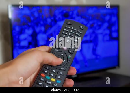 Hand holding tv remote, concept of watching television. Close up hand holding tv controller and changing channels. Stock Photo