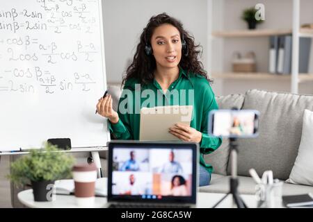 Female teacher in headset explaining math to students online Stock Photo